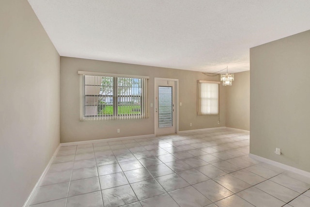 unfurnished room featuring light tile patterned floors, a textured ceiling, and a chandelier