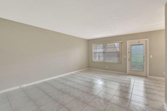 spare room featuring light tile patterned flooring and a textured ceiling