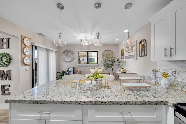 kitchen with light stone counters, decorative backsplash, decorative light fixtures, and white cabinets