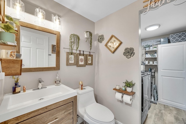 bathroom featuring wood-type flooring, toilet, washing machine and dryer, and vanity