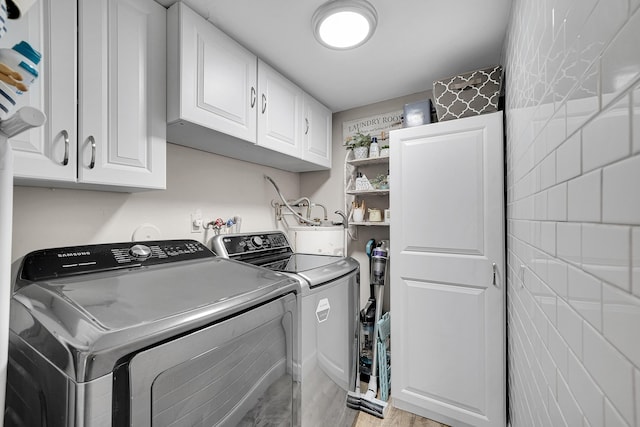 clothes washing area featuring cabinets and washer and dryer