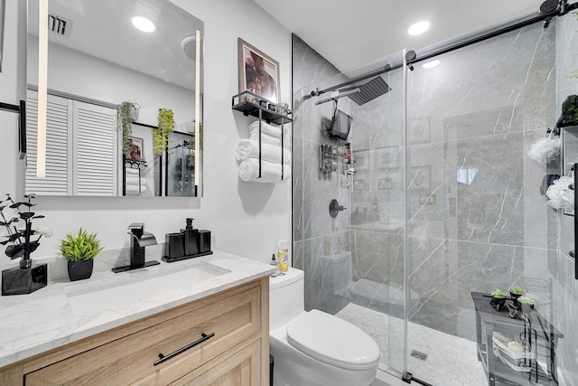 bathroom with vanity, toilet, and a shower with shower door