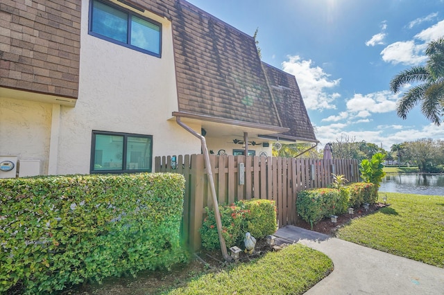 view of home's exterior featuring a water view and a lawn