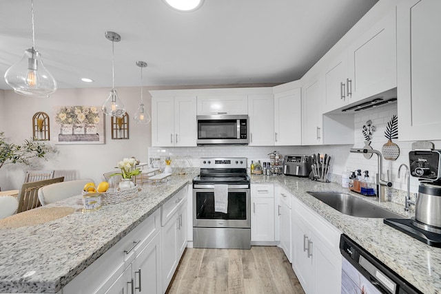 kitchen with sink, white cabinetry, hanging light fixtures, light hardwood / wood-style flooring, and stainless steel appliances