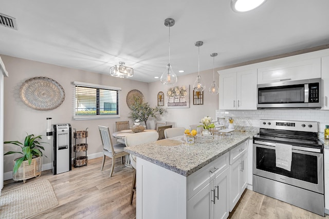 kitchen featuring stainless steel appliances, light stone countertops, white cabinets, and kitchen peninsula