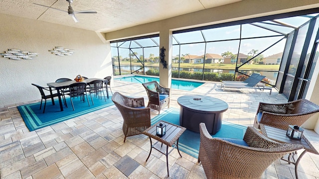 view of patio with ceiling fan, a water view, and glass enclosure