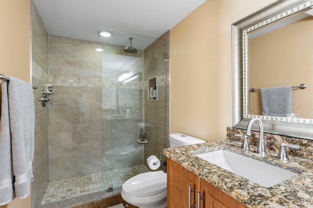 bathroom featuring vanity, tiled shower, and toilet