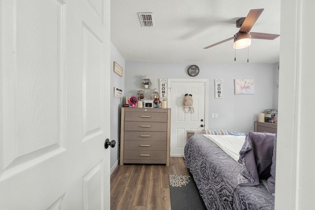 bedroom featuring ceiling fan, a textured ceiling, and dark hardwood / wood-style flooring