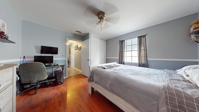 bedroom featuring hardwood / wood-style flooring, a textured ceiling, and ceiling fan