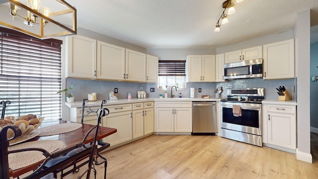 kitchen featuring stainless steel appliances, tasteful backsplash, sink, and light hardwood / wood-style floors