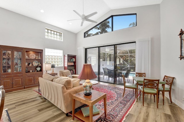 living room featuring ceiling fan, high vaulted ceiling, and light wood-type flooring