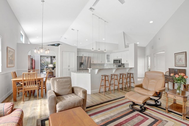 living room featuring high vaulted ceiling and light hardwood / wood-style floors