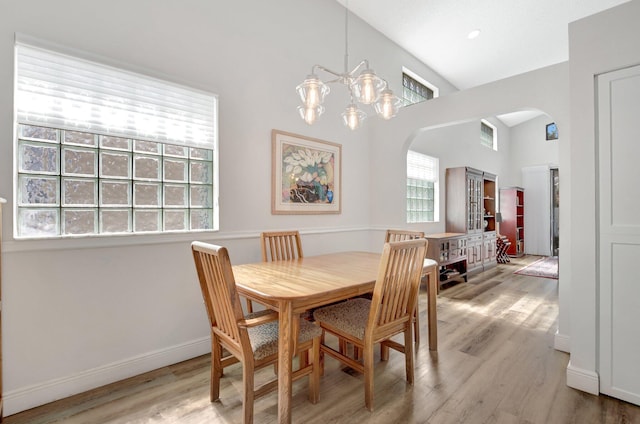 dining space featuring lofted ceiling, a notable chandelier, and light hardwood / wood-style flooring