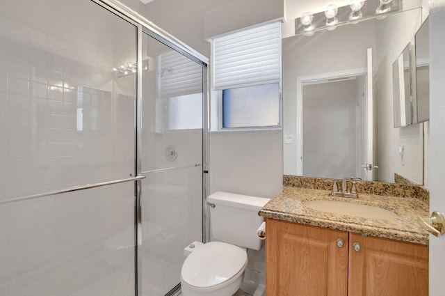 bathroom featuring vanity, a shower with door, and toilet