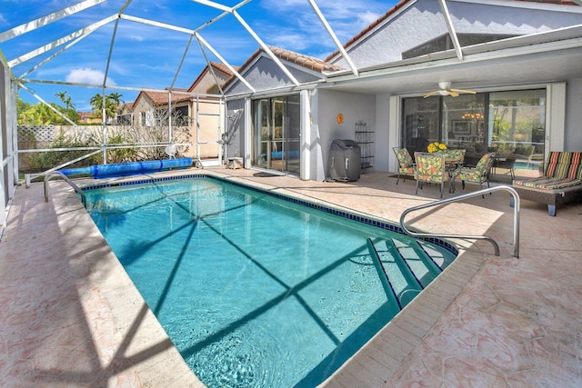 view of pool with a patio, ceiling fan, and glass enclosure