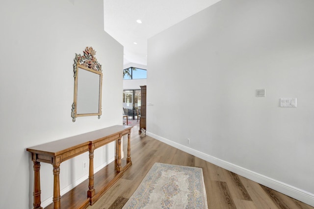 hall featuring light hardwood / wood-style floors and a high ceiling