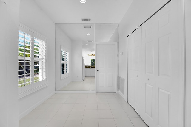 hallway featuring light tile patterned flooring and a healthy amount of sunlight