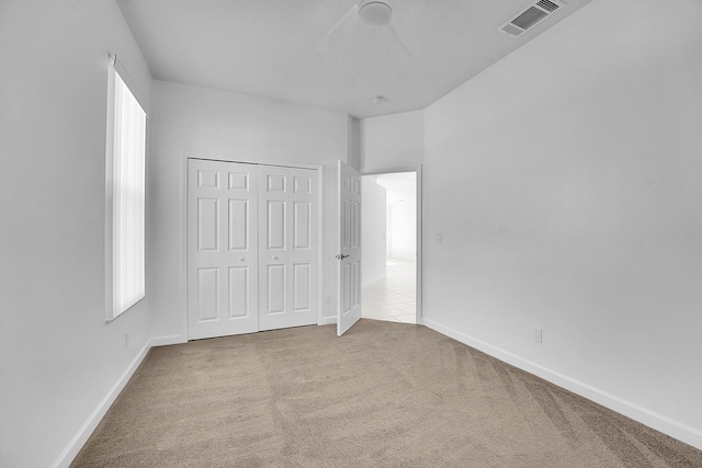 unfurnished bedroom with light colored carpet and a closet