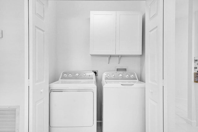 clothes washing area with washer and clothes dryer and cabinets