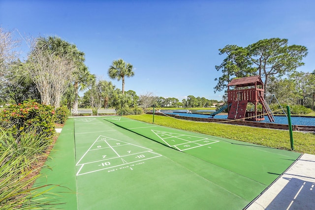 view of community featuring a playground, a water view, and a lawn