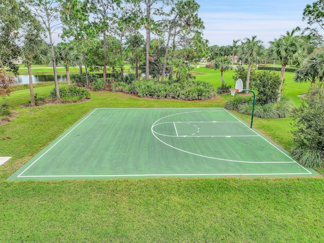 view of sport court with a water view and a yard