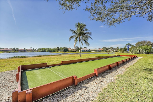 surrounding community with a water view and a lawn