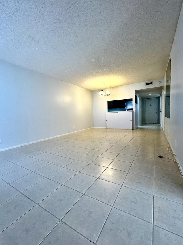 unfurnished room with light tile patterned floors, a notable chandelier, and a textured ceiling