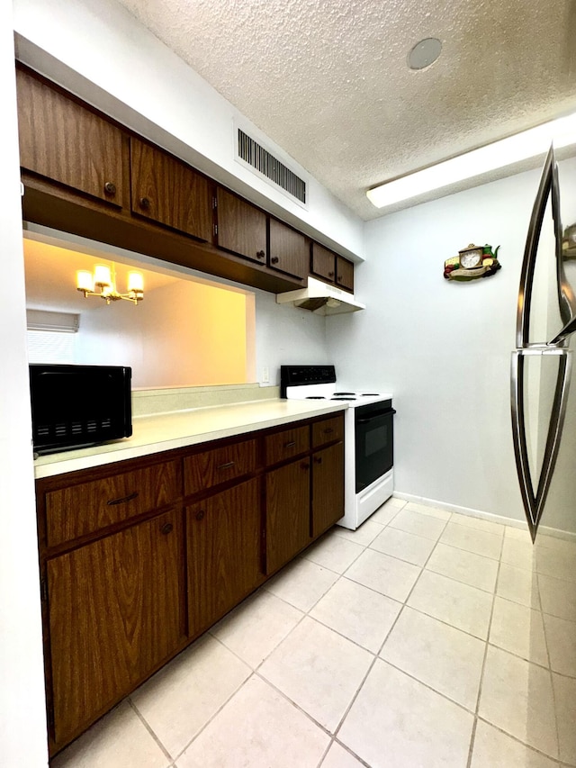 kitchen featuring fridge, dark brown cabinetry, light tile patterned flooring, and electric range oven