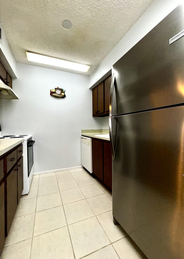 kitchen with white appliances, dark brown cabinets, a textured ceiling, and light tile patterned flooring