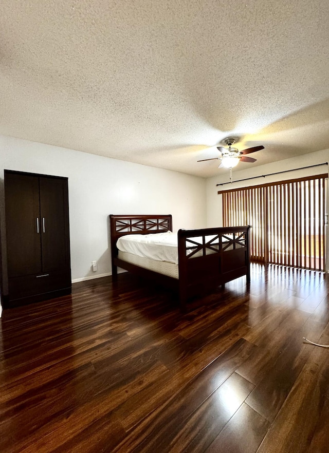 bedroom featuring ceiling fan, dark wood-type flooring, and a textured ceiling