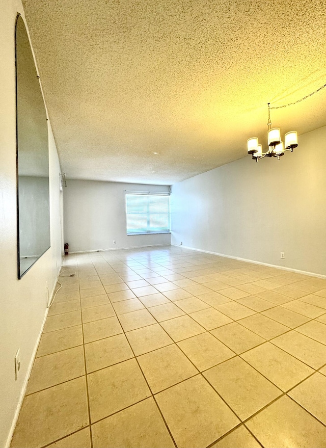 spare room with light tile patterned flooring, a notable chandelier, and a textured ceiling