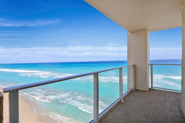 balcony featuring a view of the beach and a water view