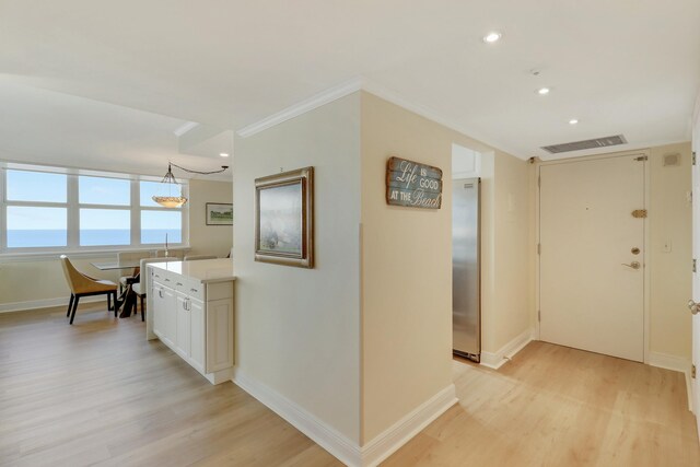 kitchen with sink, a water view, light stone counters, decorative light fixtures, and white cabinets