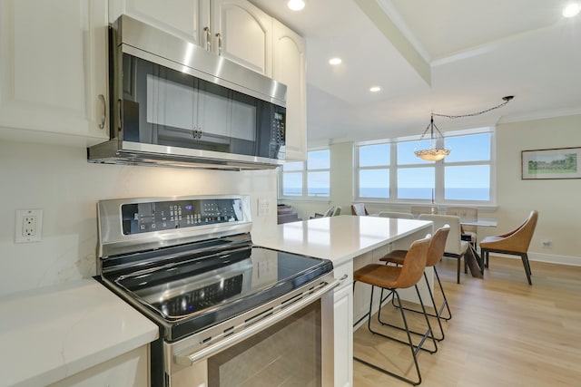 kitchen featuring white cabinetry, stainless steel appliances, crown molding, and plenty of natural light