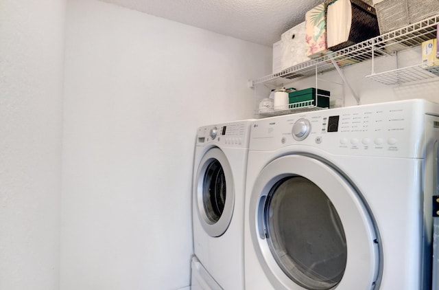 washroom featuring washing machine and clothes dryer and a textured ceiling