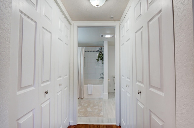 corridor featuring hardwood / wood-style floors and a textured ceiling