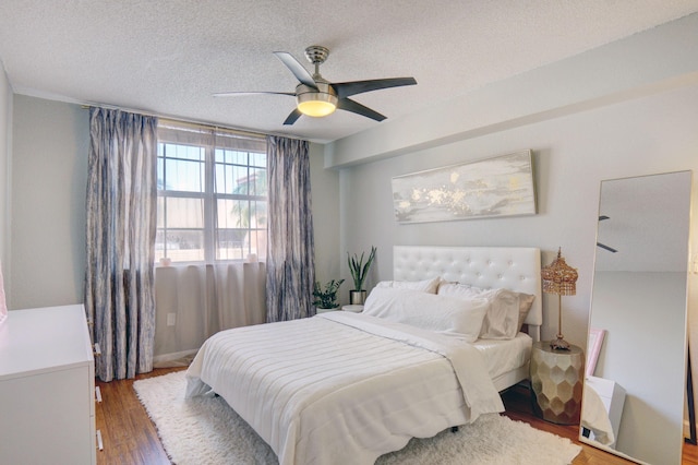 bedroom featuring ceiling fan, wood-type flooring, and a textured ceiling