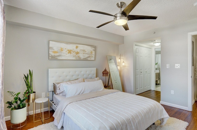 bedroom featuring ceiling fan, dark hardwood / wood-style flooring, a closet, and a textured ceiling