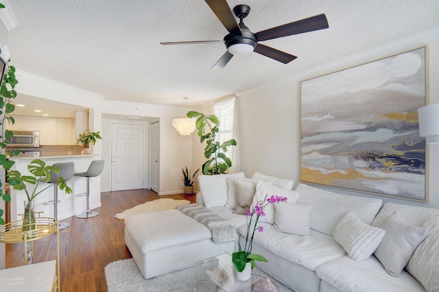 living room featuring ornamental molding, dark wood-type flooring, ceiling fan, and a textured ceiling