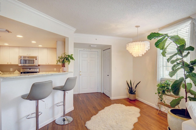 kitchen featuring decorative light fixtures, stainless steel appliances, dark hardwood / wood-style floors, and white cabinets