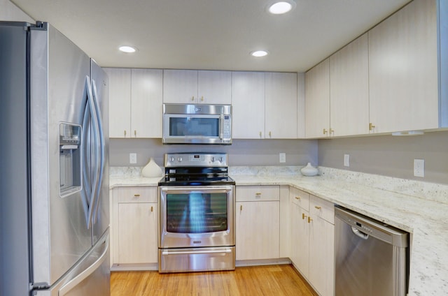 kitchen with light stone countertops, light hardwood / wood-style floors, and appliances with stainless steel finishes