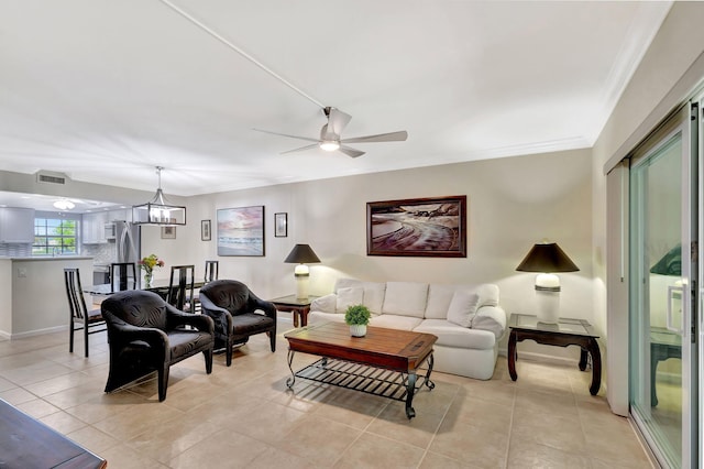 tiled living room with crown molding and ceiling fan with notable chandelier