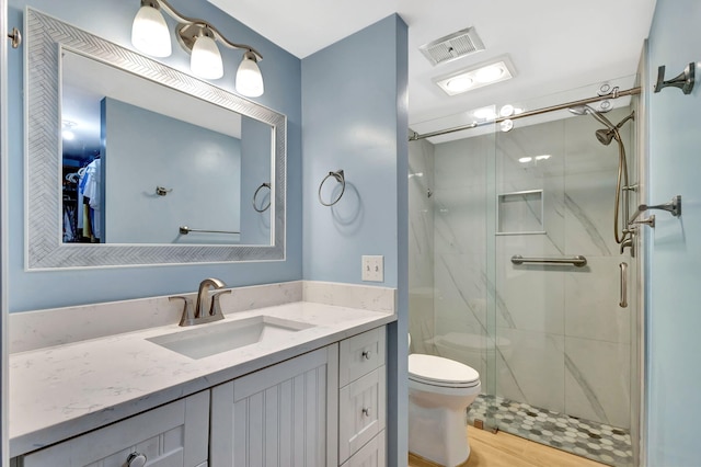 bathroom with vanity, a shower with door, and toilet