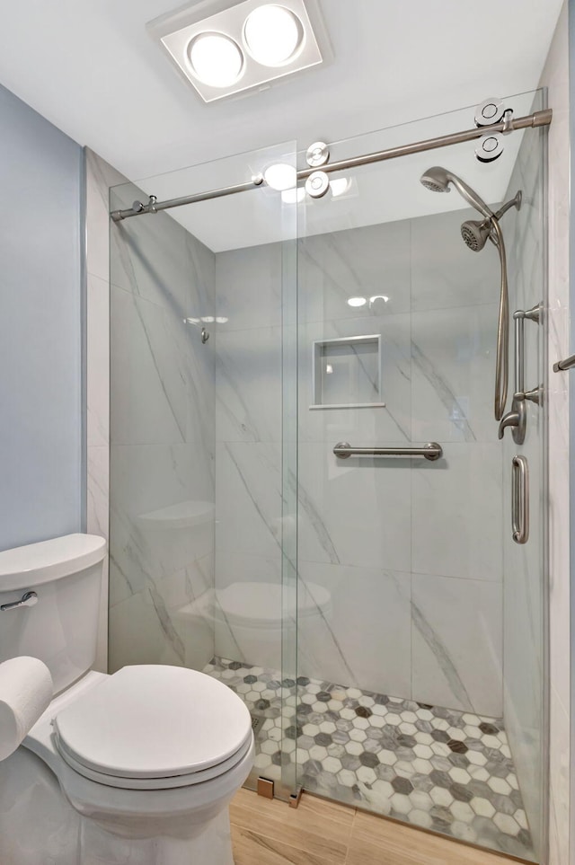 bathroom featuring toilet and a shower with shower door