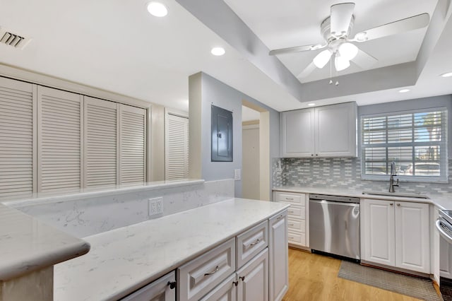 kitchen featuring sink, dishwasher, electric panel, decorative backsplash, and light wood-type flooring