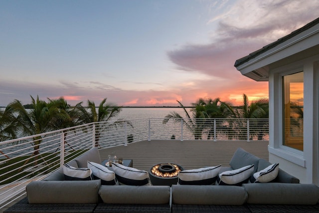 deck at dusk featuring a water view and a fire pit