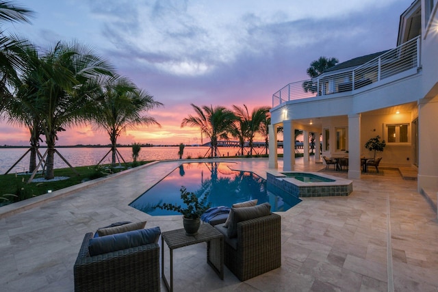 pool at dusk featuring a water view, an in ground hot tub, and a patio area