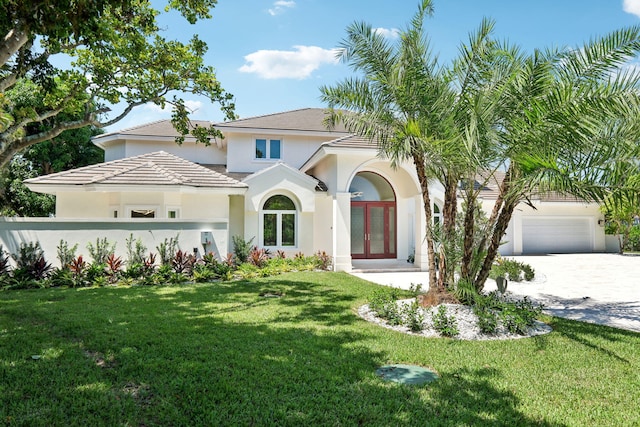 mediterranean / spanish-style house featuring a garage, a front lawn, and french doors