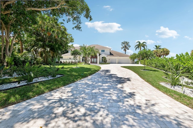 mediterranean / spanish-style home with a garage and a front lawn