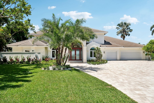 mediterranean / spanish house featuring french doors, a garage, and a front yard